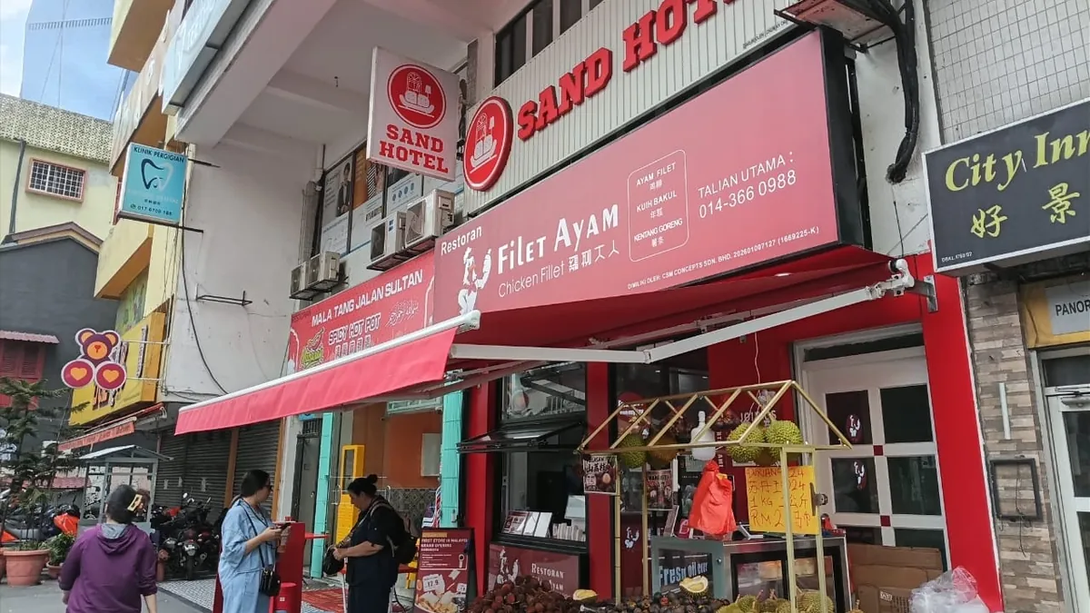 A red folding-arm awning over the front of a restaurant on a city street