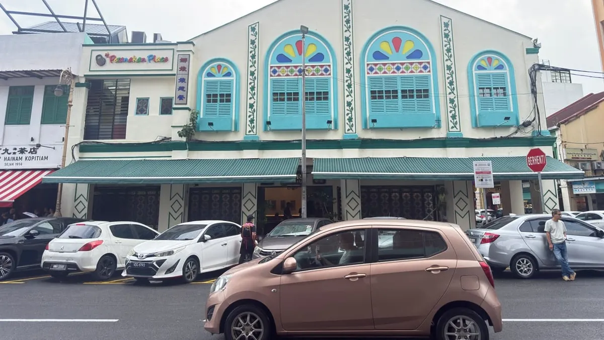 Two green striped folding-arm awnings along the front of a restored heritage shophouse
