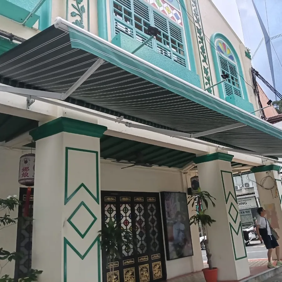 A green striped folding-arm awning on a heritage shophouse